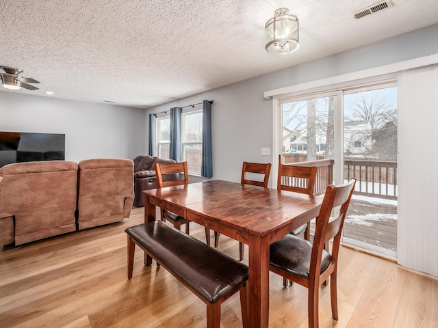 dining room featuring a textured ceiling, ceiling fan, light hardwood / wood-style floors, and a wealth of natural light