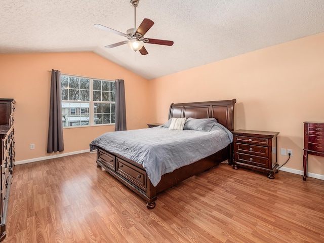 bedroom with ceiling fan, light wood-type flooring, lofted ceiling, and a textured ceiling