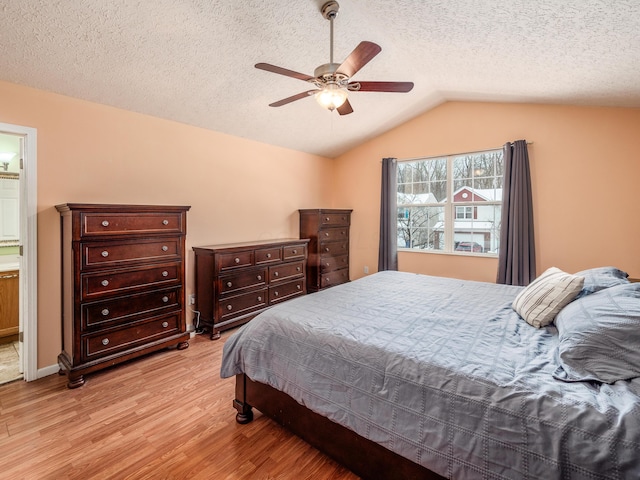 bedroom featuring a textured ceiling, lofted ceiling, ceiling fan, light hardwood / wood-style floors, and ensuite bath