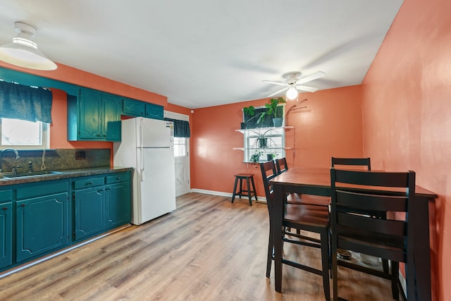 kitchen featuring white refrigerator, sink, ceiling fan, tasteful backsplash, and light hardwood / wood-style flooring