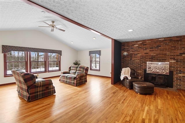 living room with a textured ceiling, ceiling fan, light hardwood / wood-style floors, and lofted ceiling