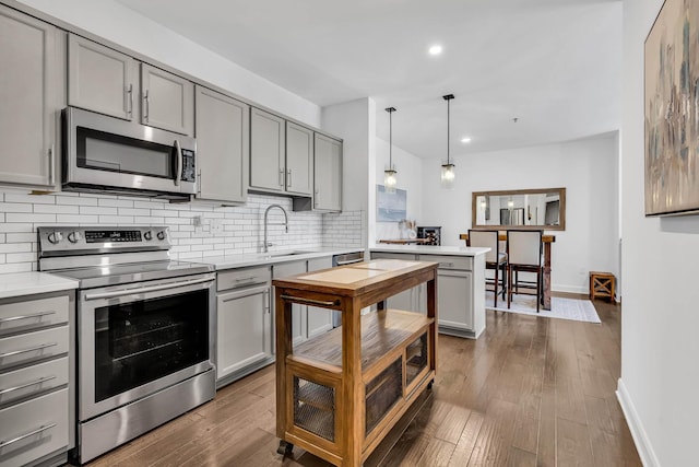 kitchen featuring dark hardwood / wood-style flooring, stainless steel appliances, sink, hanging light fixtures, and gray cabinetry