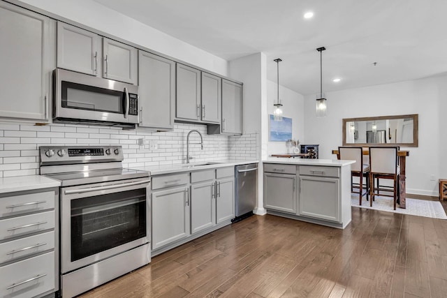 kitchen featuring sink, decorative light fixtures, kitchen peninsula, stainless steel appliances, and gray cabinets