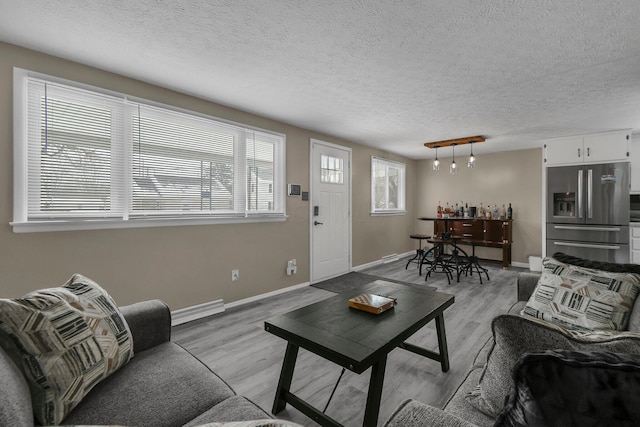 living room featuring baseboard heating, light hardwood / wood-style flooring, and a wealth of natural light