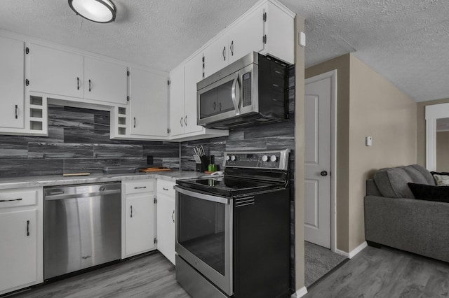 kitchen with white cabinets, stainless steel appliances, decorative backsplash, and wood-type flooring