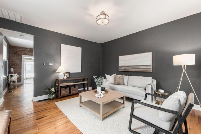 living room with brick wall and hardwood / wood-style flooring