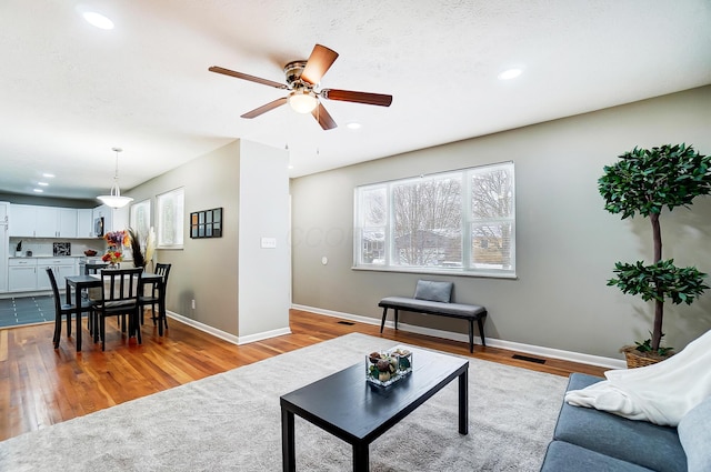 living room with light hardwood / wood-style floors and ceiling fan