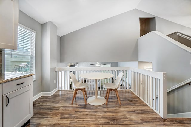 dining space featuring dark wood-type flooring and vaulted ceiling