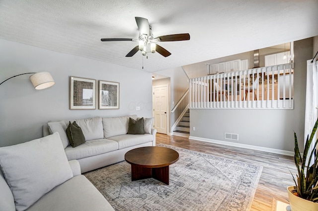 living room with ceiling fan, a textured ceiling, and hardwood / wood-style flooring