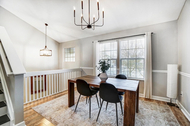 dining area featuring light wood-type flooring, vaulted ceiling, and an inviting chandelier