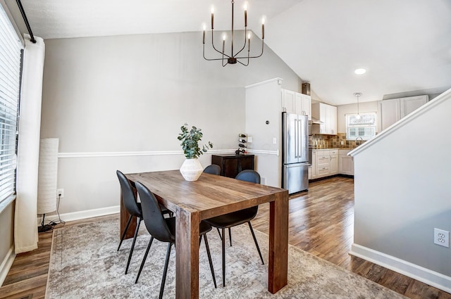 dining area with lofted ceiling, a chandelier, and hardwood / wood-style flooring