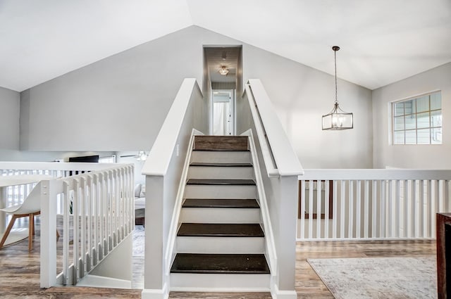 staircase with lofted ceiling, a chandelier, and wood-type flooring