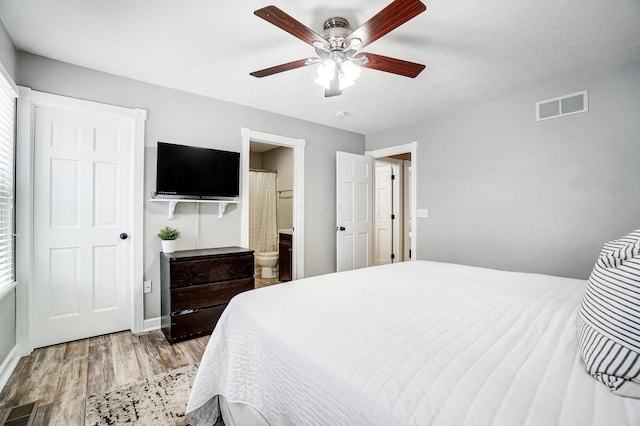 bedroom with ensuite bath, ceiling fan, and hardwood / wood-style flooring