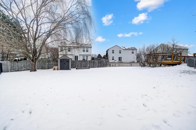 yard covered in snow with a wooden deck, cooling unit, and a storage shed