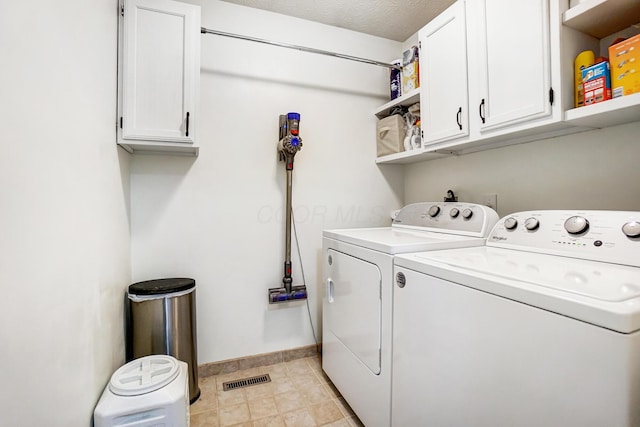 laundry area with a textured ceiling, cabinets, and washing machine and clothes dryer