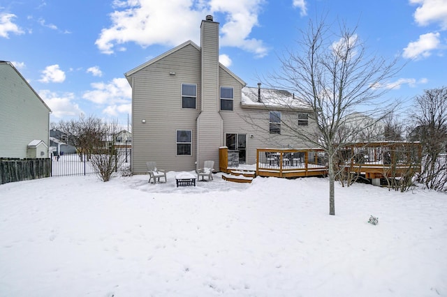 snow covered back of property with a deck