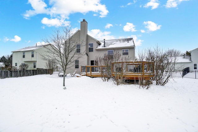 snow covered rear of property with a deck