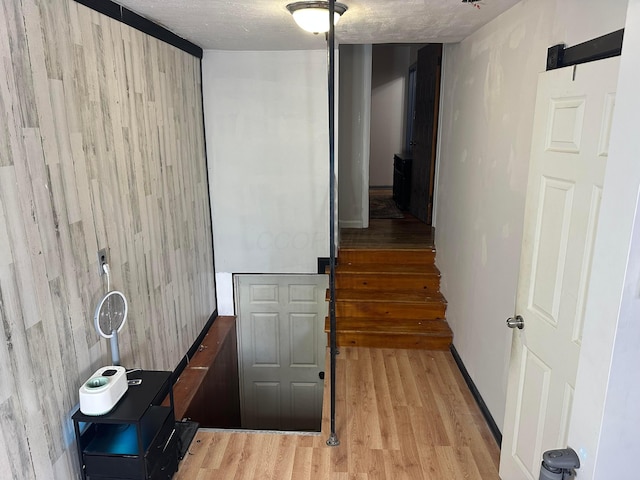 corridor featuring wood-type flooring, wood walls, and a textured ceiling