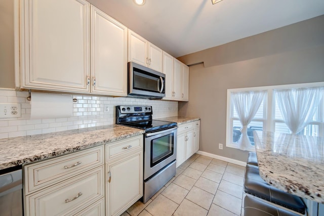 kitchen with stainless steel appliances, tasteful backsplash, light tile patterned floors, and light stone counters