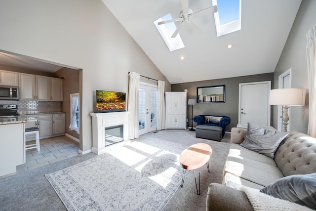 tiled living room with high vaulted ceiling, a skylight, and ceiling fan