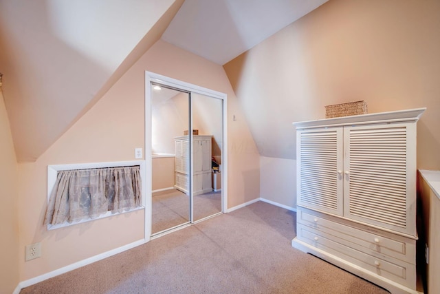 unfurnished bedroom featuring lofted ceiling, light colored carpet, and a closet