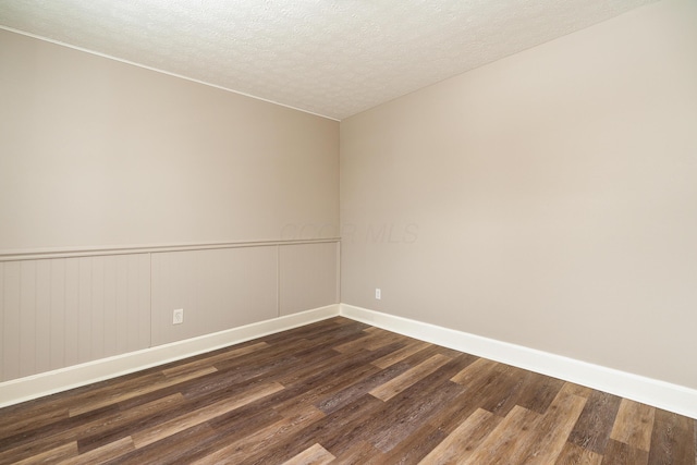 spare room with a textured ceiling and dark wood-type flooring