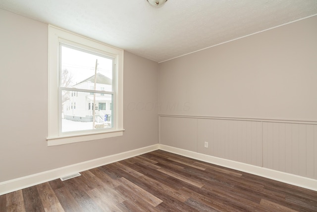 spare room featuring dark hardwood / wood-style flooring and a wealth of natural light