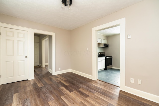 empty room with dark hardwood / wood-style floors and a textured ceiling