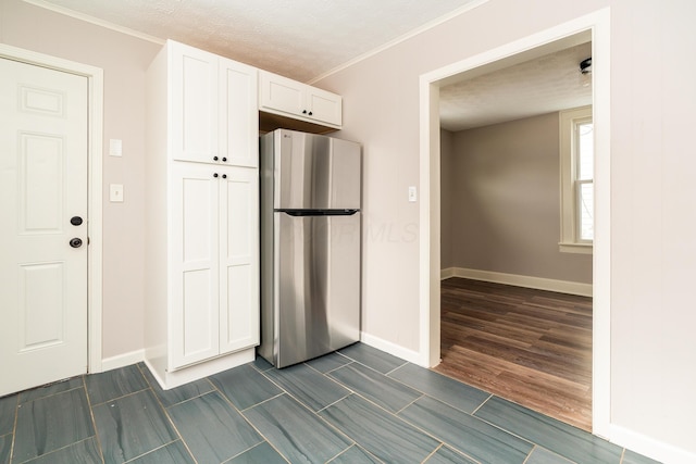 kitchen featuring a textured ceiling, white cabinetry, ornamental molding, and stainless steel fridge