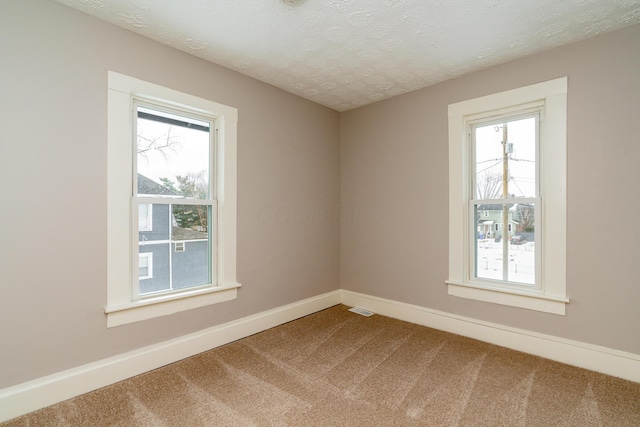 carpeted empty room featuring a textured ceiling