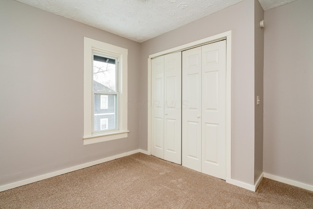 unfurnished bedroom with a textured ceiling, a closet, and carpet floors