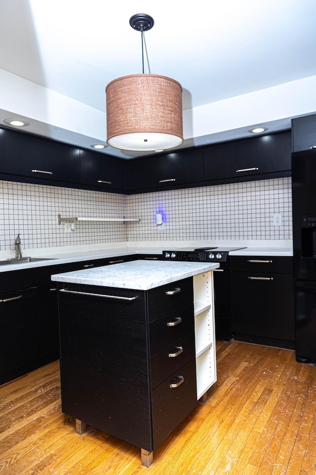 kitchen featuring black refrigerator with ice dispenser, backsplash, pendant lighting, and a center island