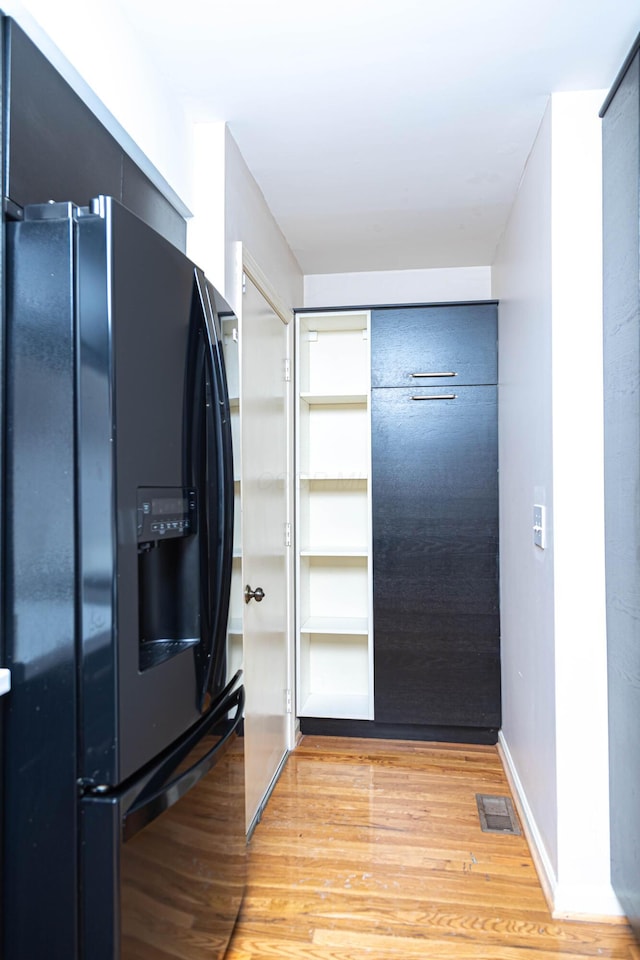 kitchen with light hardwood / wood-style floors and black fridge with ice dispenser