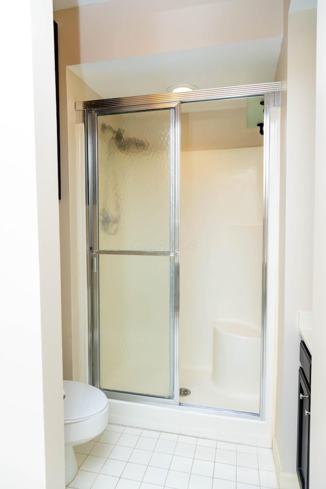 bathroom featuring toilet, tile patterned flooring, an enclosed shower, and vanity