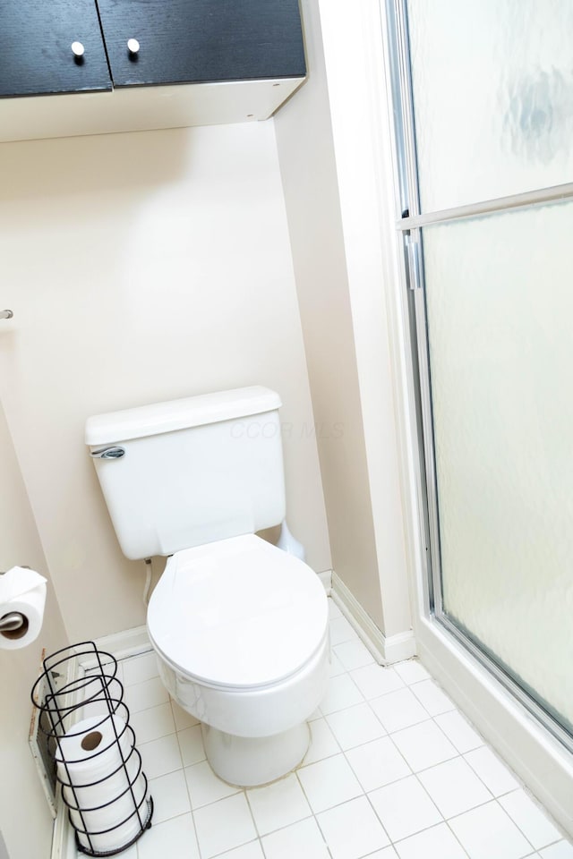 bathroom featuring toilet, walk in shower, and tile patterned floors