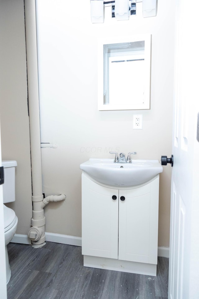 bathroom with toilet, vanity, and hardwood / wood-style floors