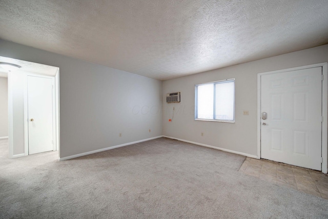 carpeted spare room featuring an AC wall unit and a textured ceiling