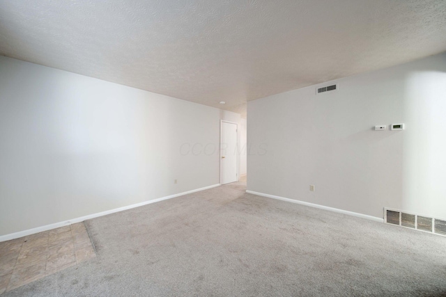 unfurnished room featuring a textured ceiling and light colored carpet