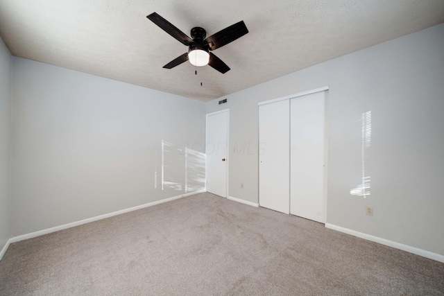 unfurnished bedroom featuring a textured ceiling, ceiling fan, a closet, and carpet floors