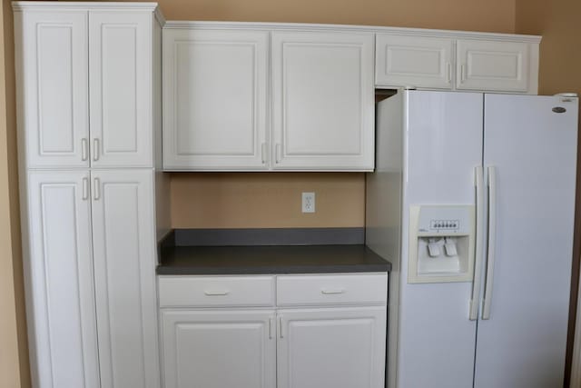 kitchen with white fridge with ice dispenser and white cabinetry