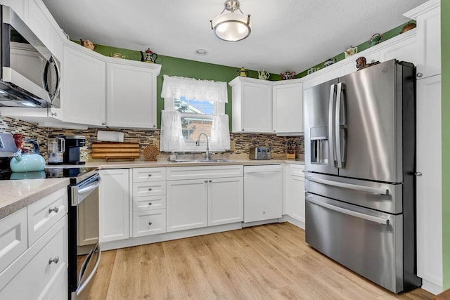 kitchen featuring backsplash, sink, white cabinets, and appliances with stainless steel finishes