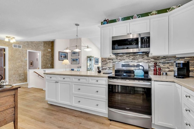 kitchen with white cabinetry, appliances with stainless steel finishes, tasteful backsplash, decorative light fixtures, and vaulted ceiling