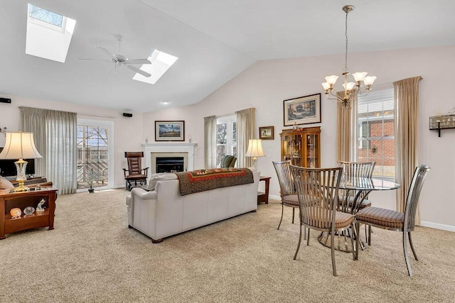 carpeted living room with lofted ceiling with skylight and ceiling fan with notable chandelier