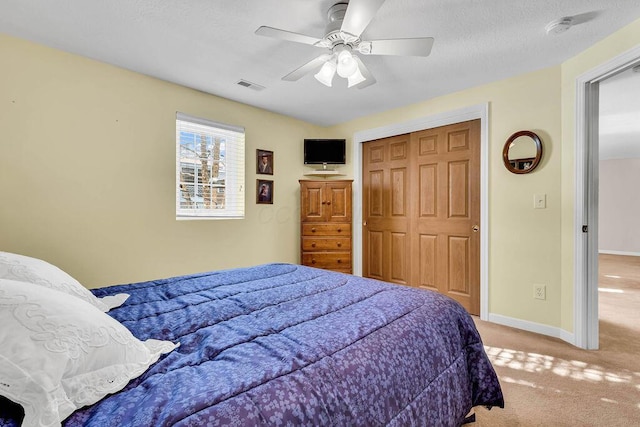 bedroom with ceiling fan, a closet, and light carpet