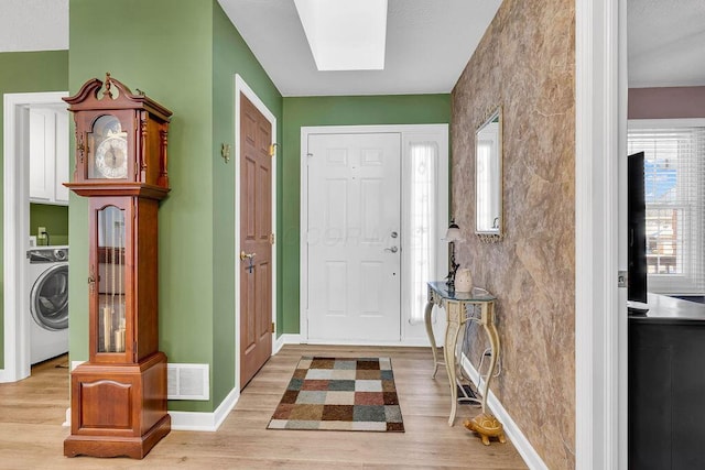 foyer featuring washer / dryer, a skylight, and light hardwood / wood-style floors