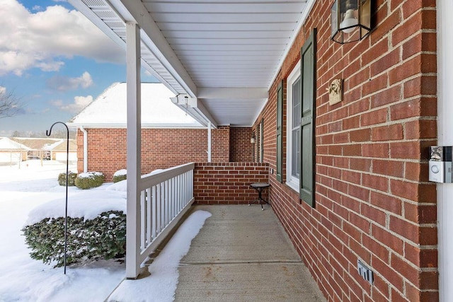 snow covered property with covered porch