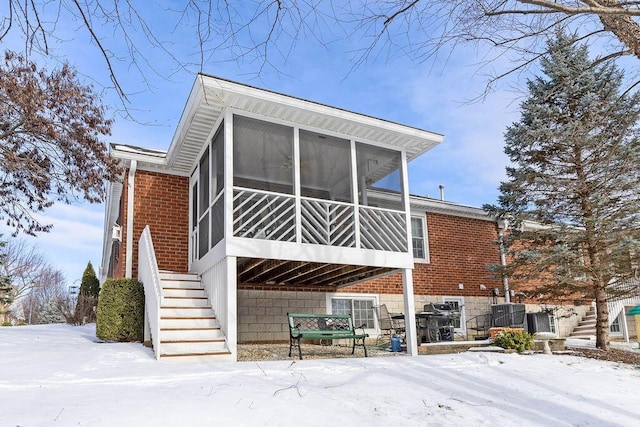 snow covered back of property with a sunroom