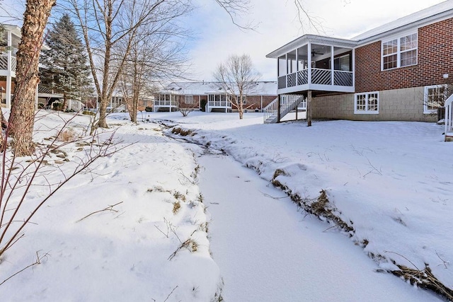 yard layered in snow featuring a sunroom