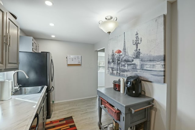 kitchen featuring light hardwood / wood-style floors, stainless steel fridge, gray cabinets, and sink