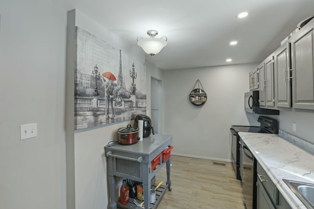 kitchen with black appliances, gray cabinetry, and light hardwood / wood-style flooring